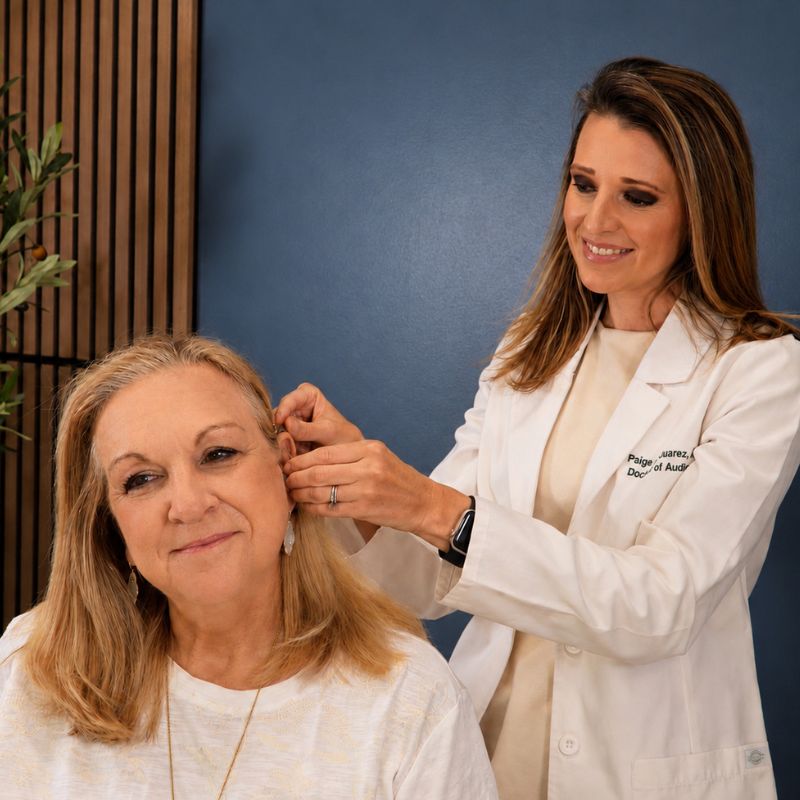 Dr. Paige Juarez fitting a hearing aid on a patient's ear at Dripping Springs Hearing & Tinnitus